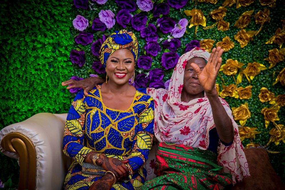 Guests posing in front of a purple and gold flower wall