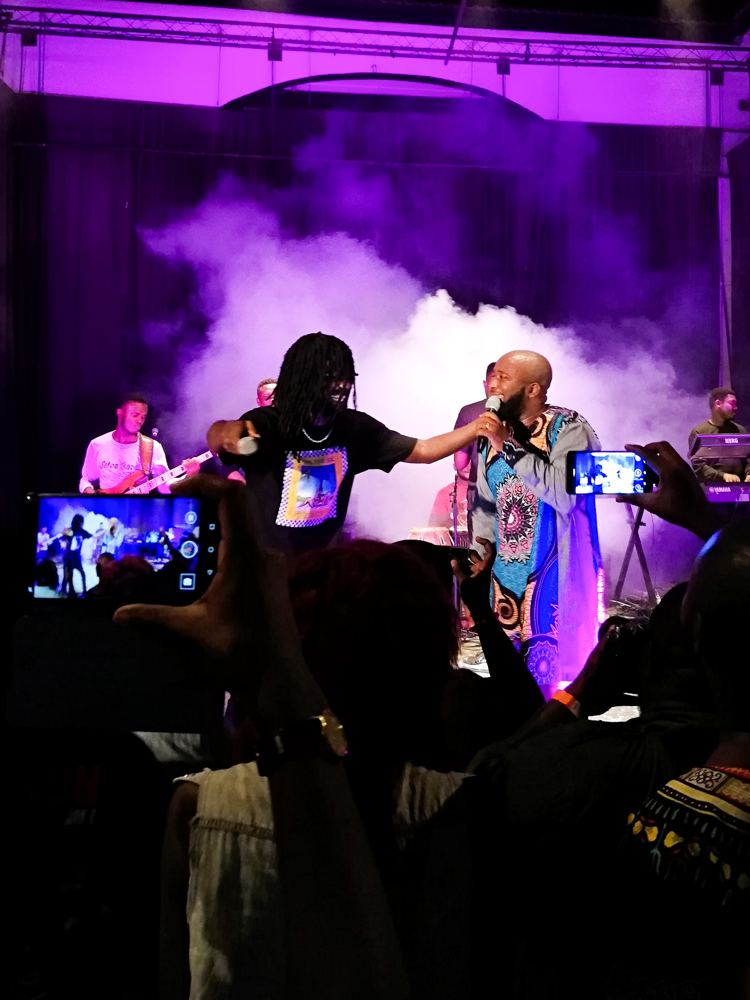 Performers on stage under purple lights at a concert in Accra