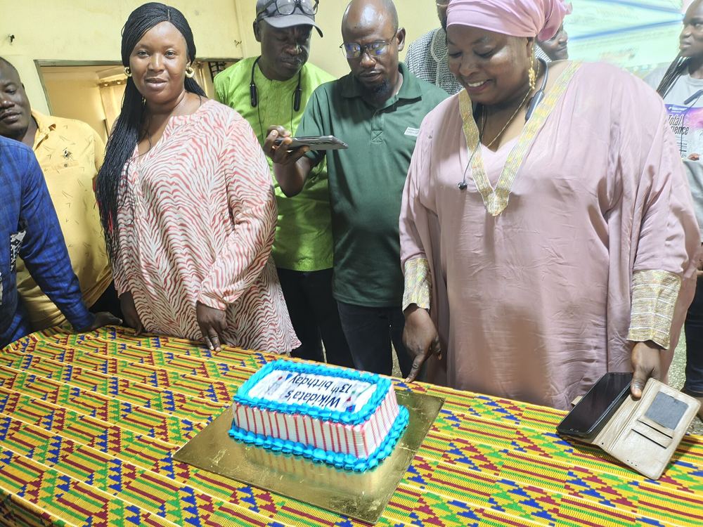 Guests gathered around a celebration cake on a kente table