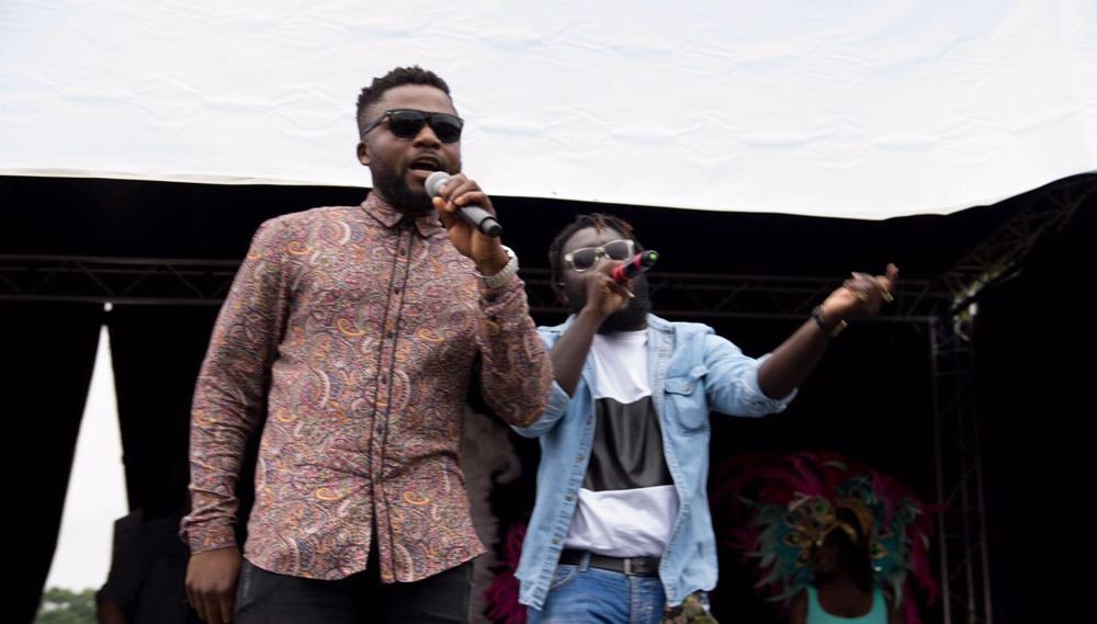 Performers with microphones on stage at an outdoor party in Ghana