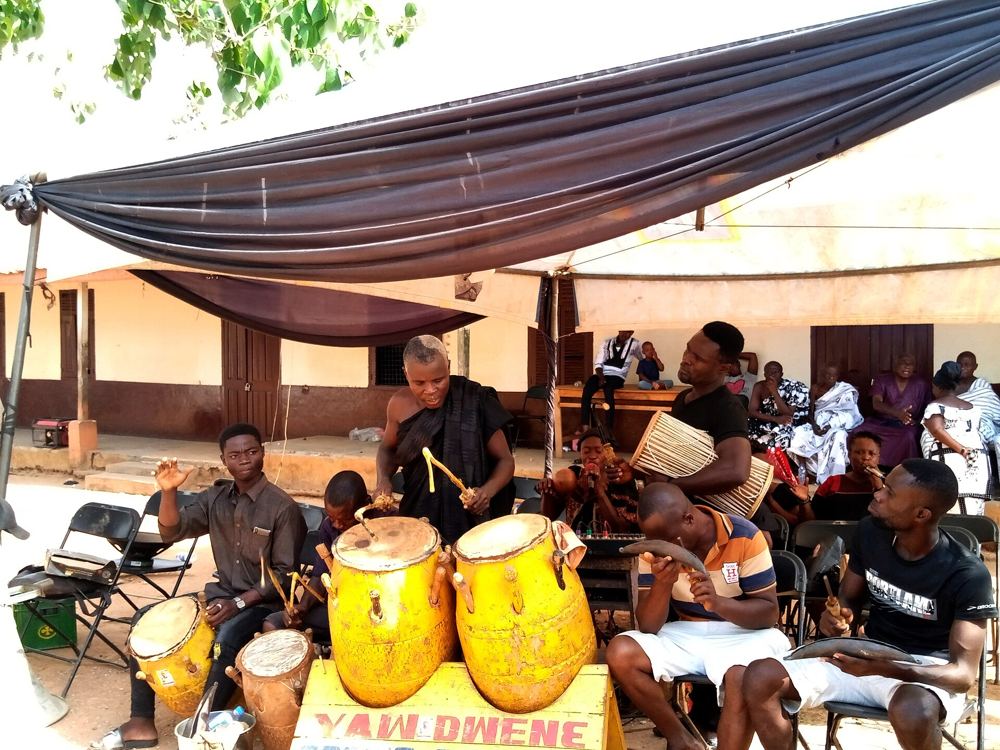 Drummers performing under a canopy at a one-week funeral celebration
